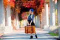 Girl in hat and shirt with suitcase in red grape alley Royalty Free Stock Photo