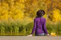 Girl in a hat sits on the dock and admires the colors of autumn. Royalty Free Stock Photo