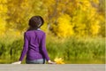 Girl in a hat sits on the dock and admires the colors of autumn. Royalty Free Stock Photo