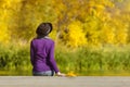 Girl in a hat sits on the dock and admires the colors of autumn. Royalty Free Stock Photo