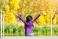 Girl in a hat sits on the dock with her hands up. Back view Royalty Free Stock Photo