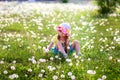The girl in a hat sits in the field of dandelions Royalty Free Stock Photo
