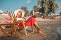 Girl with hat sitting on deck chair and reading book Royalty Free Stock Photo