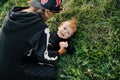 A girl in a hat and a skeleton costume plays with her younger brother on the grass in the garden. Halloween, carnival