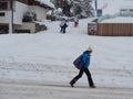 Girl with hat and Ski Suit Walking on a Cold, Snowy Day on a Snow-Covered Street and a Family with small Child Climbing on the