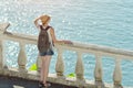 Girl in hat standing on the balcony and looking at the sea. Back Royalty Free Stock Photo