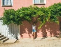 Girl in hat standing near pink wall in Turkish village