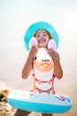 Girl in a hat it stands on the shore with inflatable circle in the shape of a lama. Inflatable alpaca for a child. Sea with a Royalty Free Stock Photo