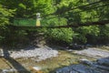 The girl in a hat strolls along a suspension bridge over a storm