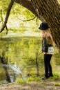 Girl in a hat walking in the park summer day and stick fishing in the river Royalty Free Stock Photo