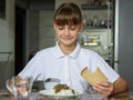 The girl is having dinner at the table, she looked at the food with appetite