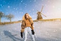 Girl having fun on ice in typical dutch landscape with windmill. Woman ice skating on rink outdoors in sunny snowy day Royalty Free Stock Photo