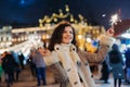 Girl having fun with sparklers on christmas decoration lights street. Young happy smilin Woman wearing stylish knitted scarf, coat