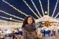 Girl having fun with sparklers on christmas decoration lights street. Young happy smilin Woman wearing stylish knitted scarf, coat