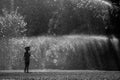 Girl is having fun in water in park, hot summer in garden, girl running in water drops,happy and cheerful girl enjoying cold water