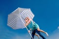 Girl having piggy back ride on a man with beach umbrella on blue Royalty Free Stock Photo