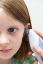 Girl Having Temperature Taken With Electronic Thermometer In Ear