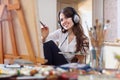 Girl in headphones paints with oil colors on canvas Royalty Free Stock Photo