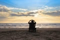 Girl in headphones is sitting on the sun lounger listening to music on the beach at sunset.