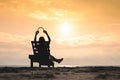 Girl in headphones is sitting on the sun lounger listening to music on the beach at sunset.