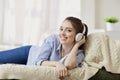 Girl in headphones smiling listening to music sitting indoor.