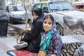 Girl in headscarf and woman in chador rest in street, Iran.
