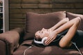 Girl with headset lying on sofa and listen music