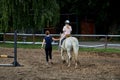 An instructor teaches a teenage girl horse riding, equestrian sports