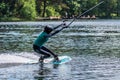 Girl with helmet and life vest rides a wakeboard on the lake