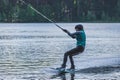 Girl with helmet and life vest rides a wakeboard on the lake