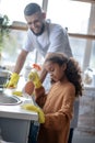 Girl helping daddy to clean kitchen at the weekend