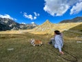 Girl with her bright red dog sitting on a hill high in the mountains Royalty Free Stock Photo