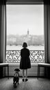 Girl and her dog are looking out over the city center through a large window