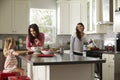 Girl with her female parents, preparing meal in the kitchen