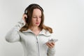 girl with her finger taps on professional headphones listen to music check quality in hands holds white smartphone Royalty Free Stock Photo