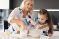 A girl with her grandmother cooks a homemade cake. They knead the dough with their hands