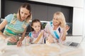 A girl with her mother and grandmother preparing homemade cookies. They make dough circles with a glass