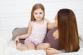 The girl and her mother sitting on white bed Royalty Free Stock Photo