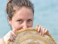 Girl hides a face behind a straw hat