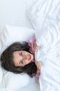 Girl hides her face in bed. Cheerful girl in bed hiding her face under the blanket. Teenage girl lying under a blanket. Woman