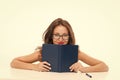 girl hiding behind book looking at camera. flirt and desire. girl read book in glasses. Introverted or extrovert girl