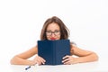 Girl hiding behind book looking at camera. flirt and desire. girl read book in glasses. Introverted or extrovert girl