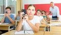 Girl high school student using mobile phone on lecture in class Royalty Free Stock Photo