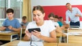 Girl high school student using mobile phone on lecture in class Royalty Free Stock Photo