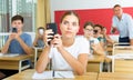 Girl high school student using mobile phone on lecture in class Royalty Free Stock Photo