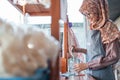 The girl in the hijab seller pours a packet of milk to make a drink