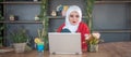 Girl with hijab typing on laptop and relaxing