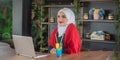 Girl with hijab typing on laptop and relaxing