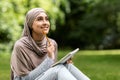 Girl in hijab writing essay, studying at public park