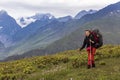 Girl hiker with hiking backpack in mountains. Tourist in Svaneti on a background of the main Caucasus ridge and snow-capped